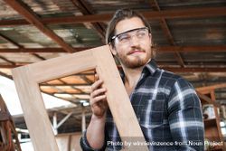 Male proud of a frame he made at his carpentry studio 5rWq74