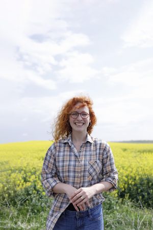 Red haired woman smiling in a field, vertical