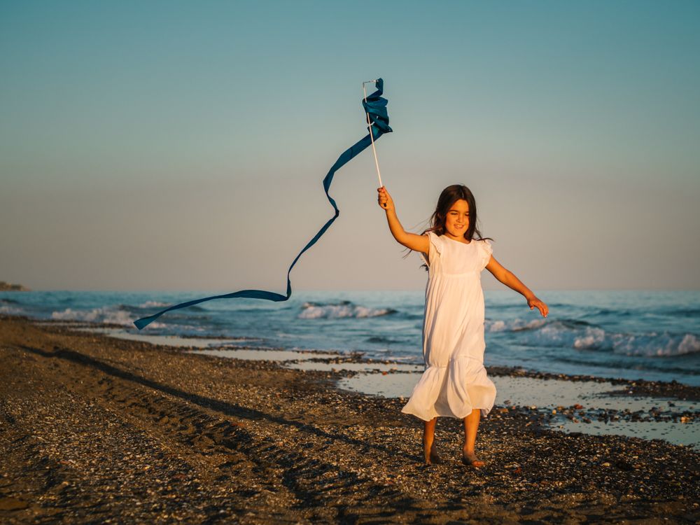 Adorable girl playing with ribbon on seaside