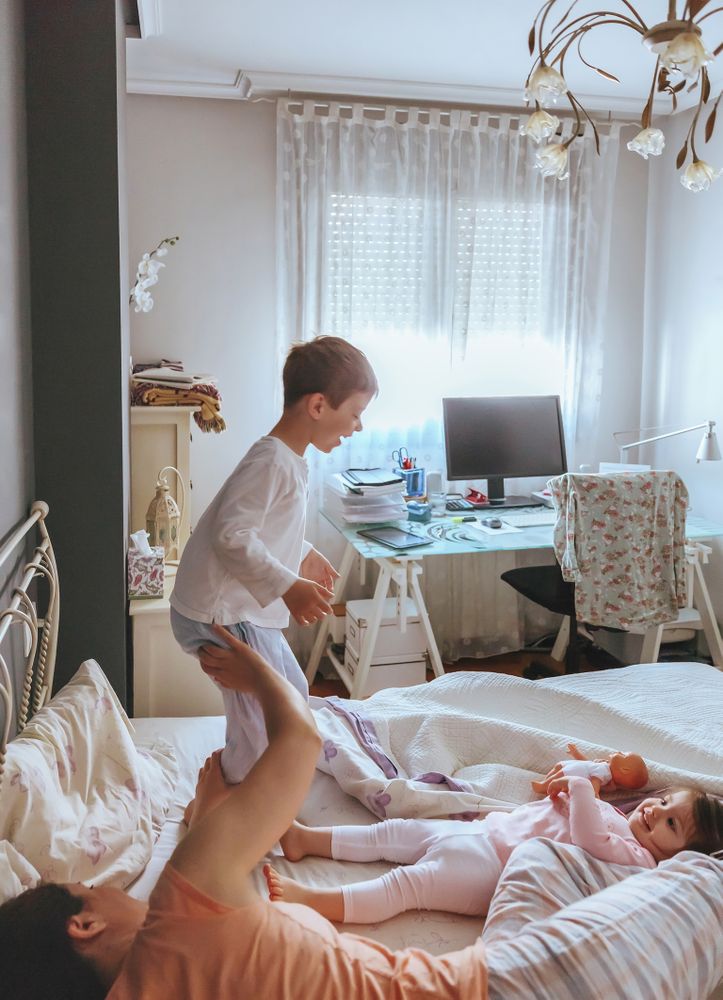 Portrait of happy boy jumping on the bed with his family on a relaxed morning