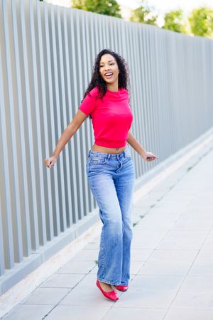 A Joyful Woman Dancing in a Vibrant and Colorful Outfit on a Bustling City Street