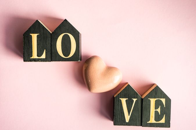 The word "love" on pastel pink background with heart ornament