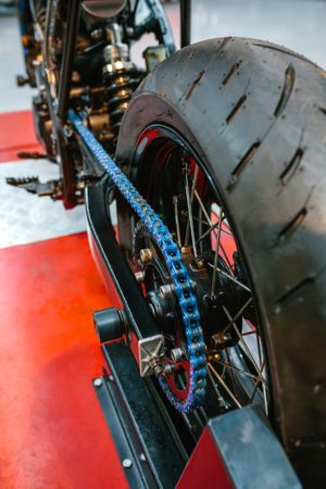 Close up of rear wheel and decorative blue chain on custom motorbike on factory