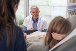 Doctor giving a serious consultation to a pregnant couple in his office.