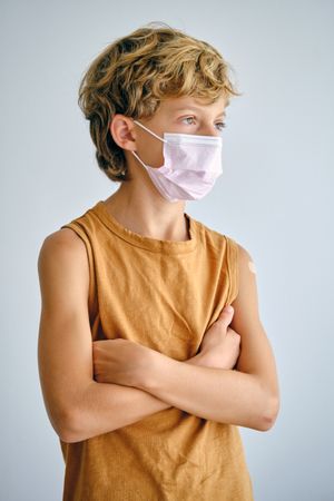 Contemplative boy in sterile mask on light background