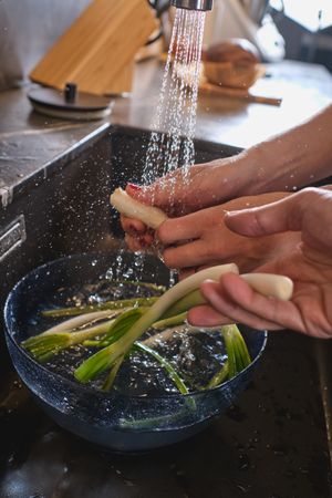Anonymous people washing green onions