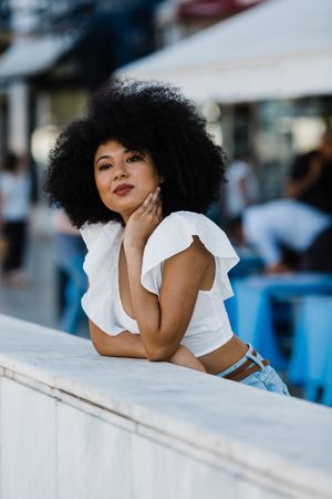 Black female leaning in concrete parapet