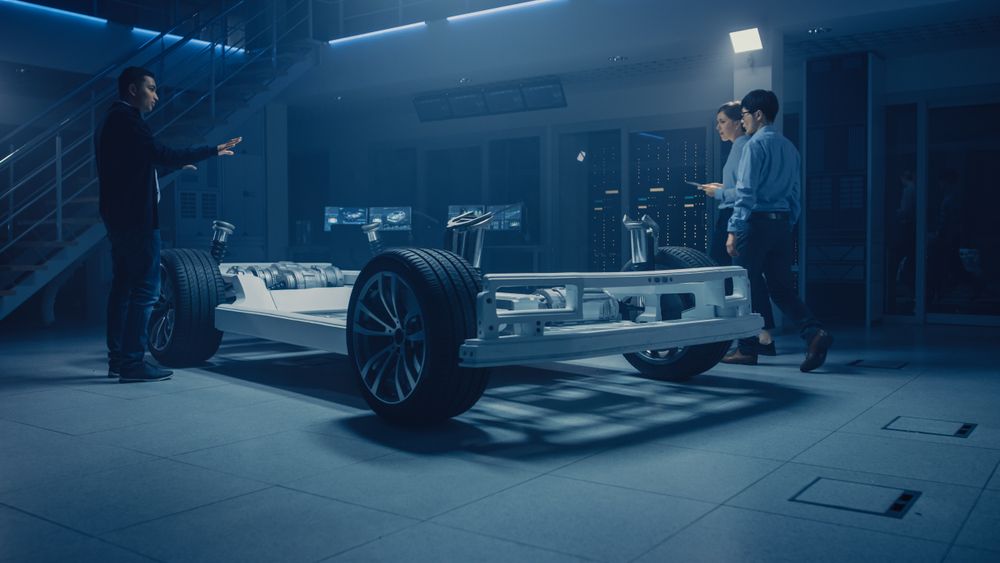 Automobile Design Engineers Talking while Working on Electric Car Chassis Prototype