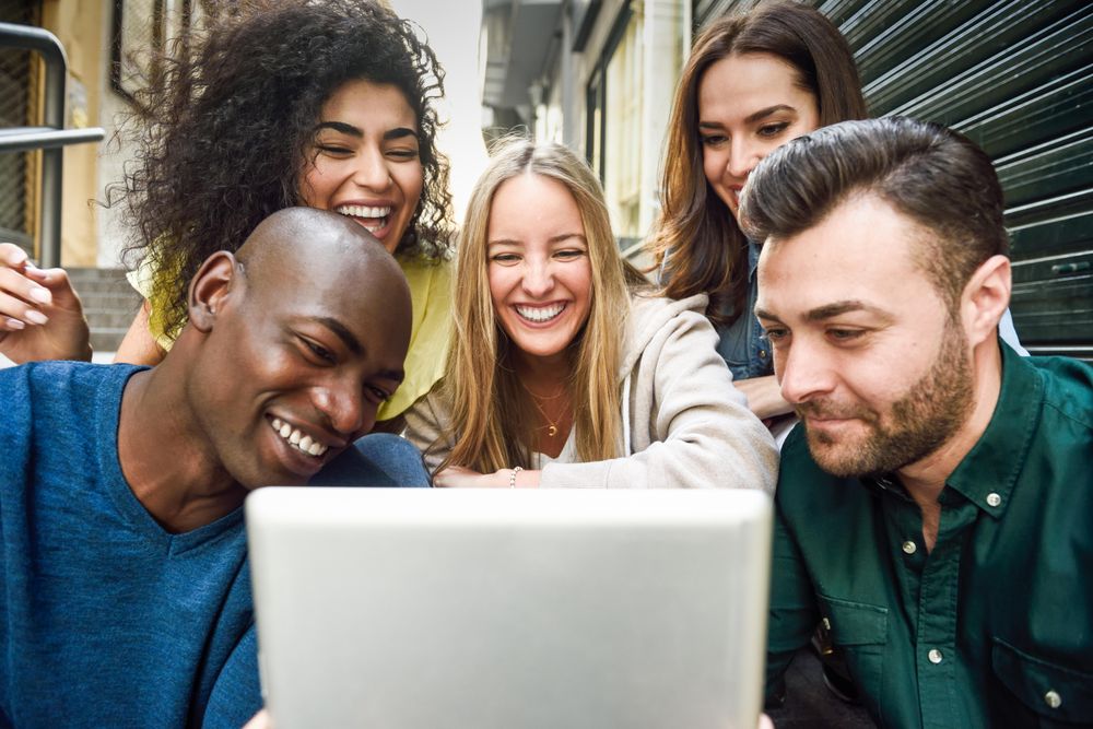 Male and female friends enjoying something on digital tablet while sitting on outdoor stairs