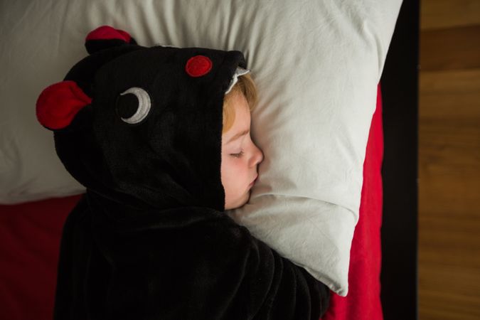 Boy in unicorn pajama sleeping in bed