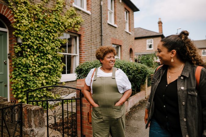 Two women talking while walking down a residential street