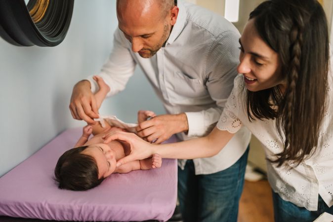 Parents changing diaper for baby