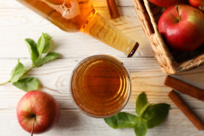Composition with cider, cinnamon and apples on wooden background