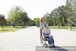 Woman pushing smiling friend in wheelchair 47d7Ob
