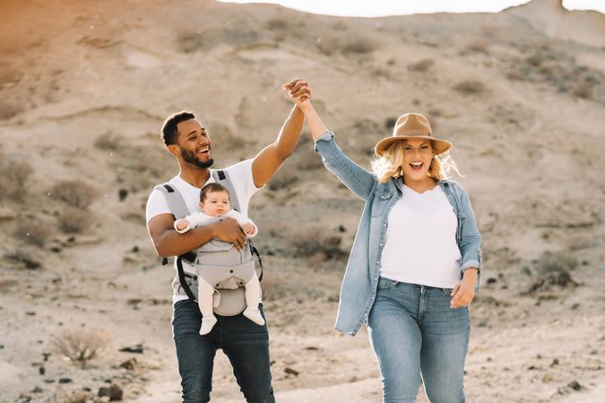 Diverse parents dancing while walking with baby