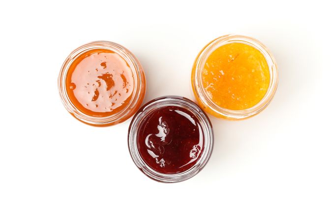 Glass jars with jam isolated on blank background