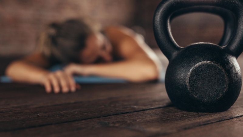 Kettle bell in front with woman lying down and rest at the back in fitness club
