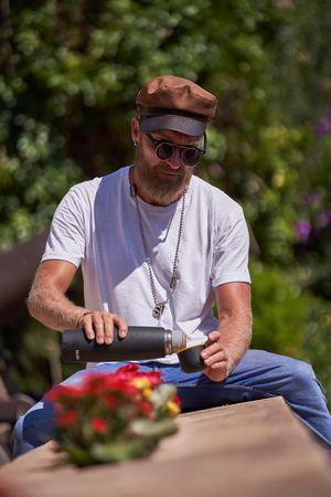 Bearded male traveler pouring tea from thermos