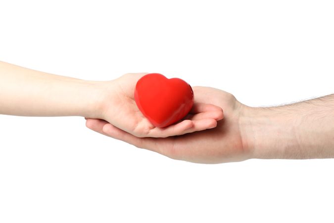 Female and male hands hold heart, isolated on plain background