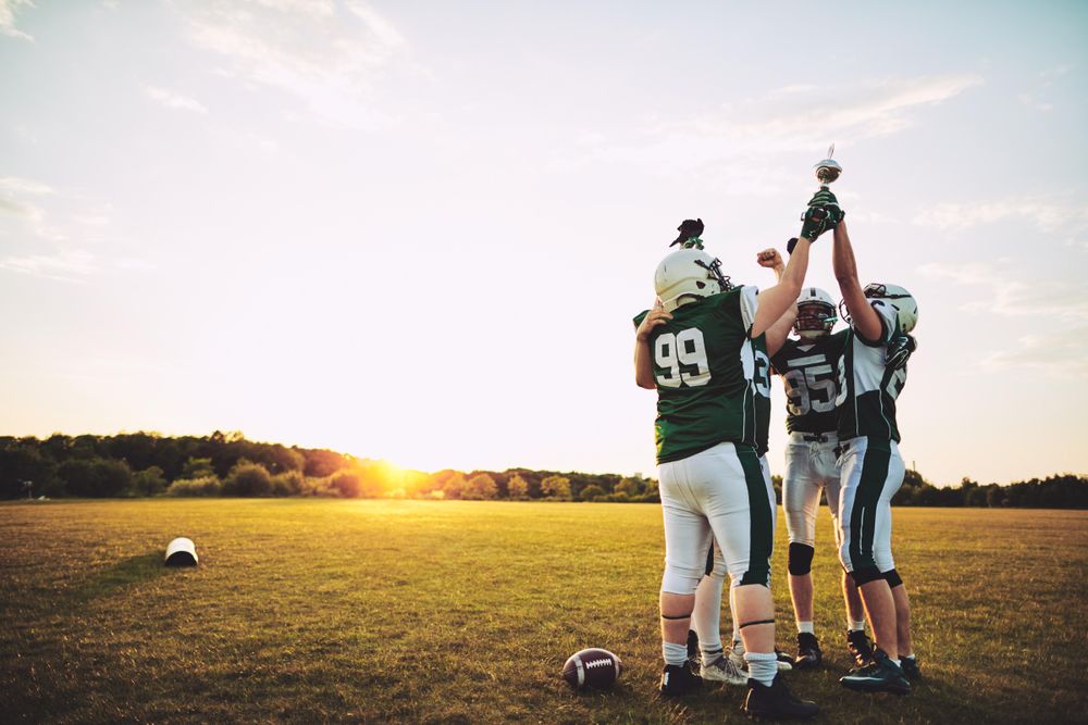 Men holding up a trophy and celebrating winning a football game