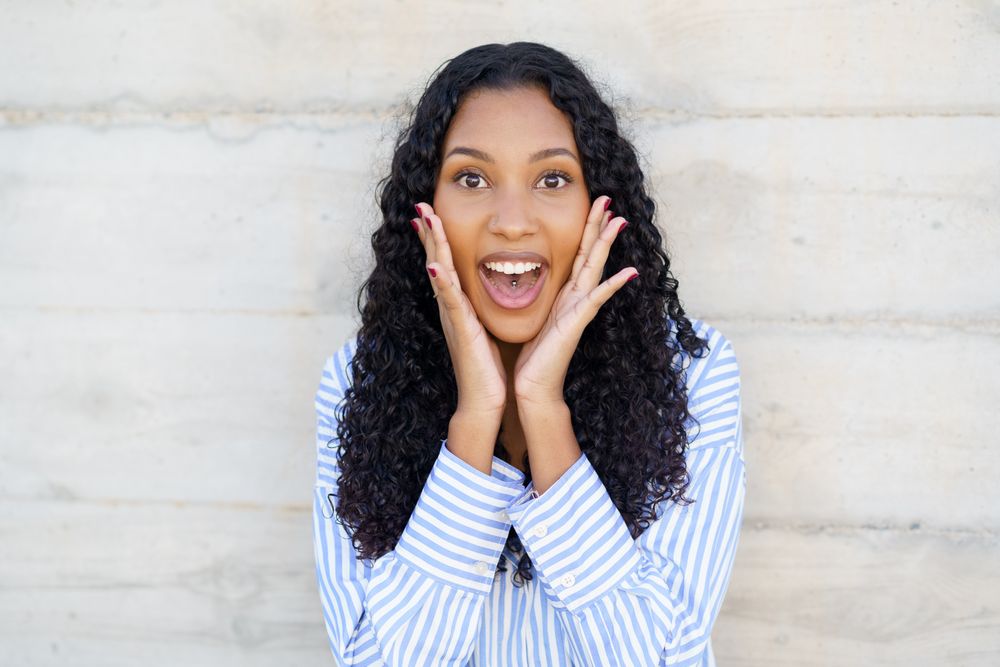 An Excited Young Woman with Beautiful Curly Hair Expressing Joy and Enthusiasm Clearly