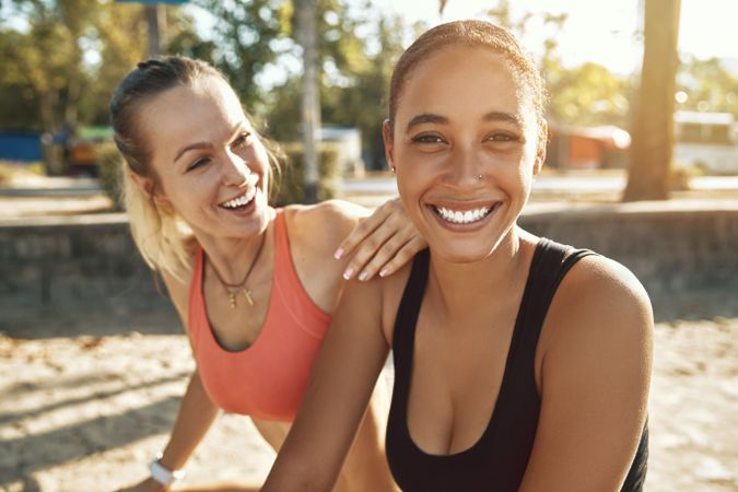 Two young women smiling together outside after a workout