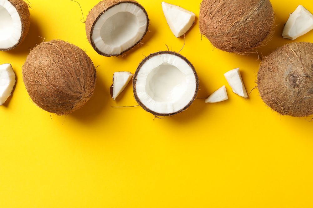 Flat lay with coconut on yellow background, space for text