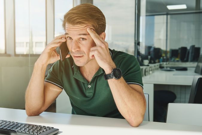 Concerned man talking on smartphone in office