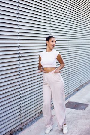 A stylish young woman poses confidently against a contemporary architectural background