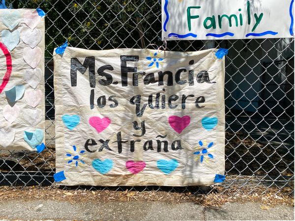 Homemade sign from a teacher to her students in Spanish taped to school fence