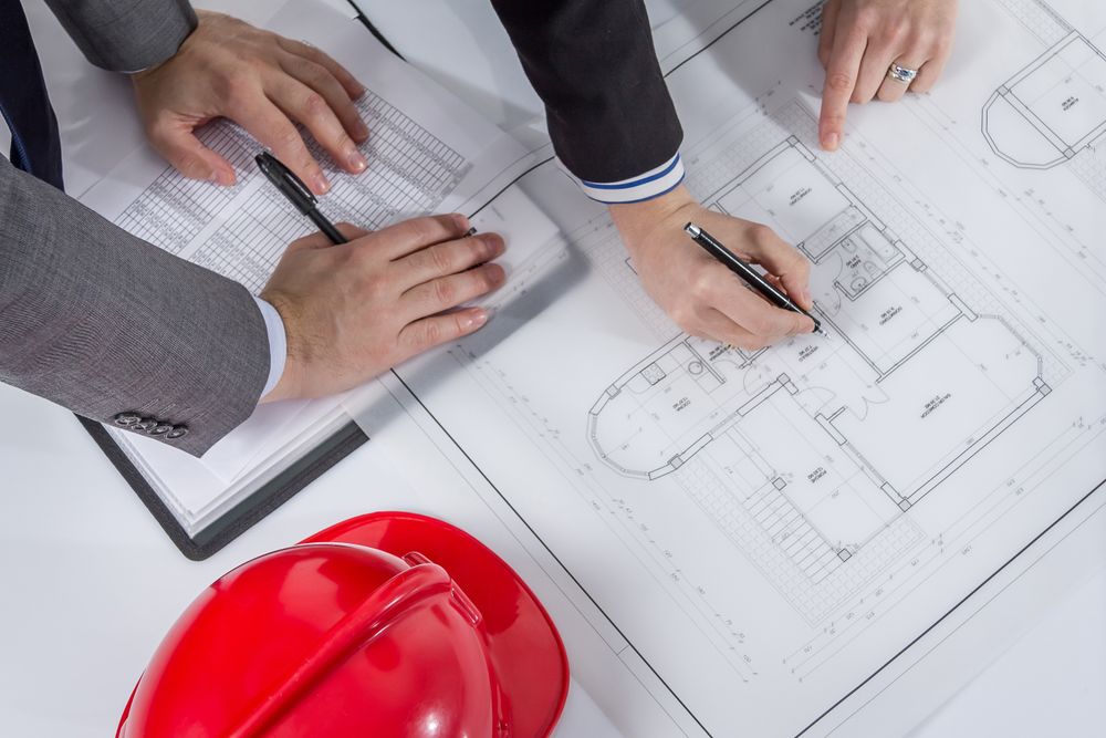 Above view of architects hands revising a house project