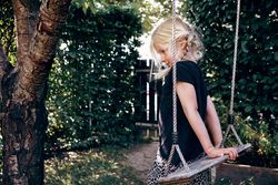 Blonde girl with braided hair sitting on outdoor swing