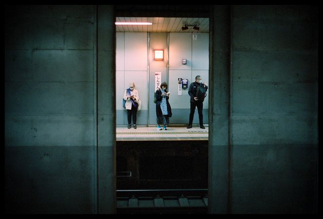 Three people waiting at the train station