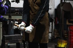Professional blacksmith making form of metal detail with hammer