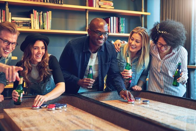 Multi-ethnic group of friends playing a bar game with beers in hand