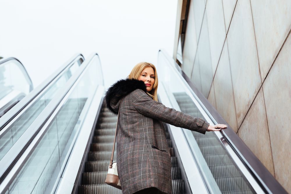 Blonde woman climbing escalators