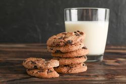 Tasty chocolate chip cookies and glass of milk on wooden table. Space for text
