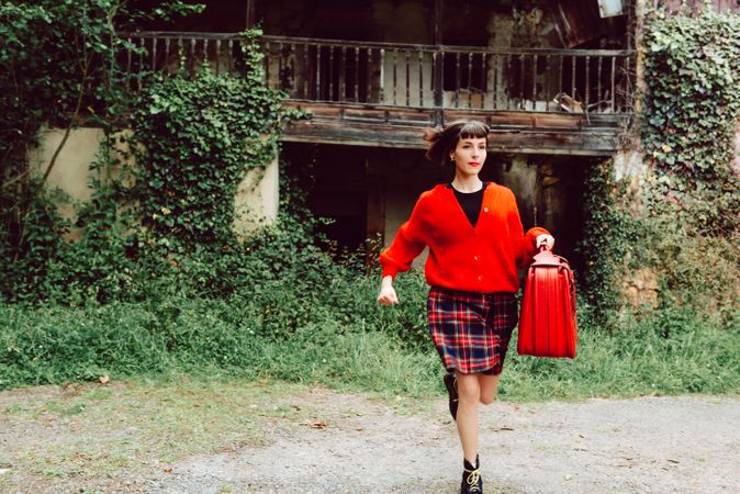 Woman in red with big red suitcase in forest