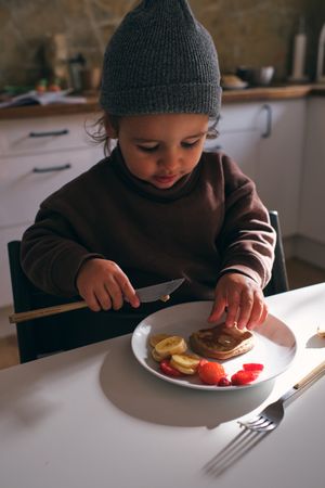 Little boy having breakfast with fruits and pancake