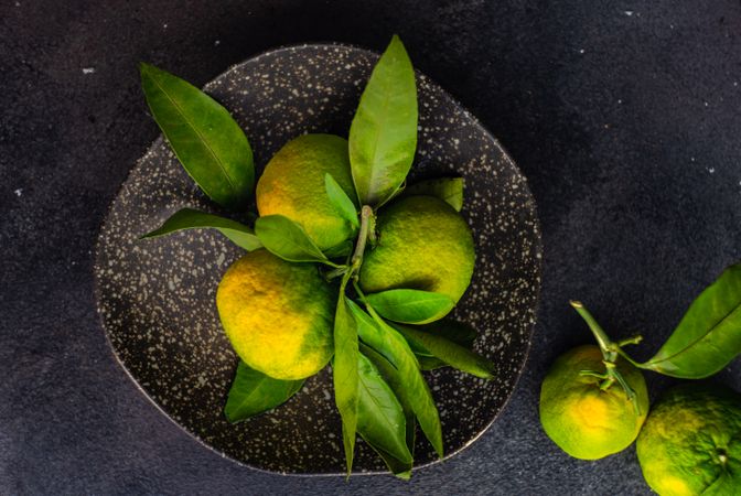 Top view of fresh green tangerines in grey ceramic bowl