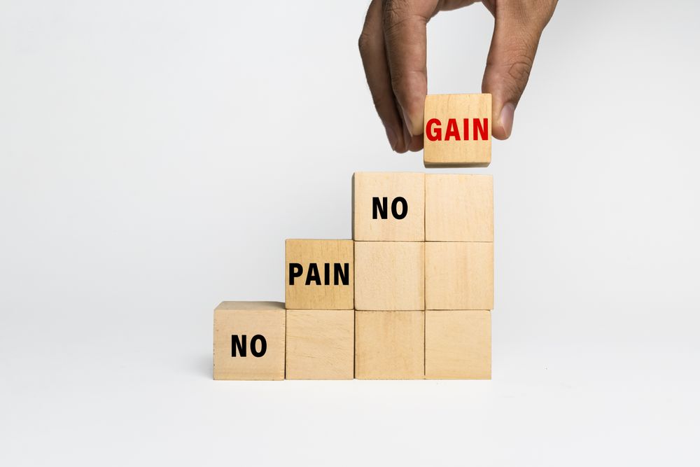 male hand put a wooden blocks with no pain no gain words isolated on plain background