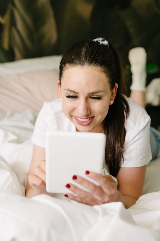 Smiling woman using tablet on bed in bedroom
