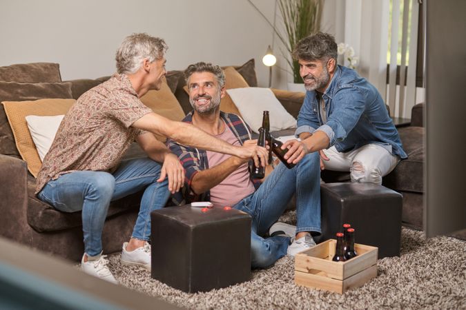 Mature men smiling and drinking beer at home