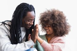 Delighted Black man cuddling with daughter
