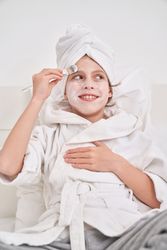 Cheerful kid applying mask on face with brush