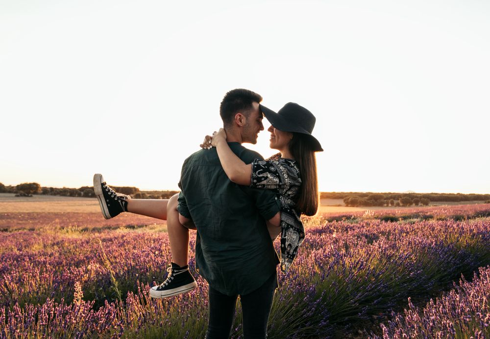 Beautiful romantic photo of a couple in a field of flowers at sunset