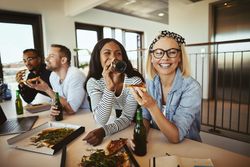 Two young businesswomen enjoying pizza lunch at work