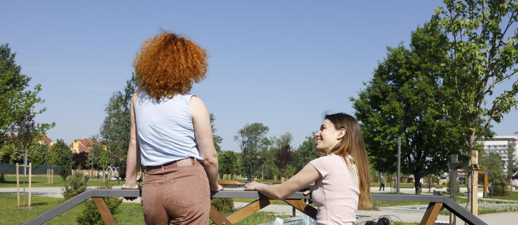 Wide shot of two women looking over a park from railing