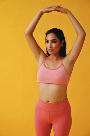 Hispanic female in yoga clothes with hands together above head