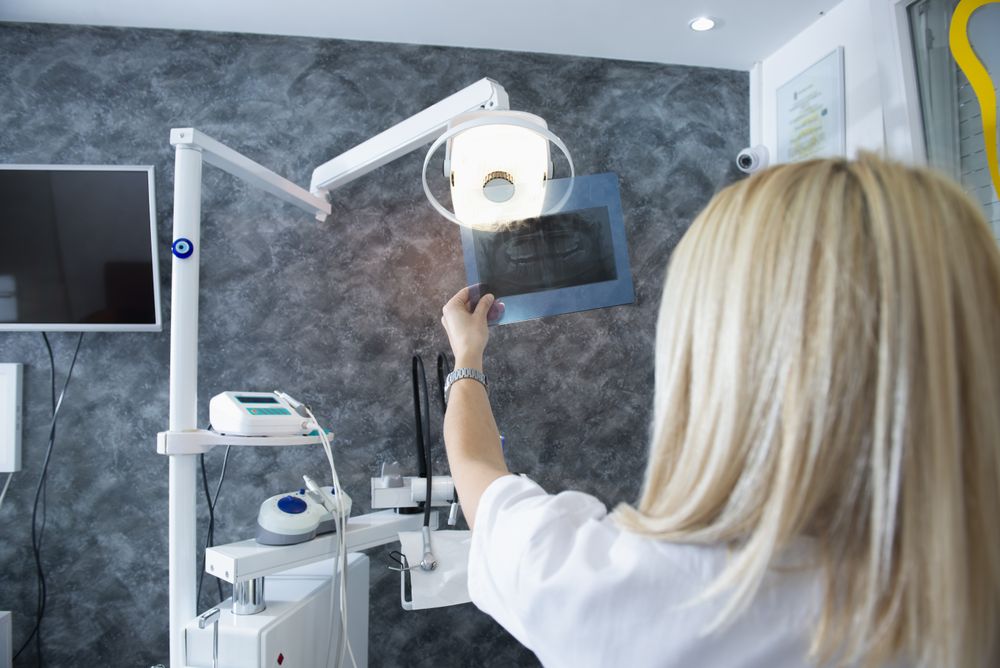 Rear view of blonde dentist looking at X-ray in office